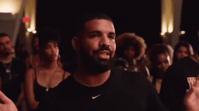 A Man With A Beard Wearing A Black Nike Shirt Is Standing In Front Of A Crowd . GIF