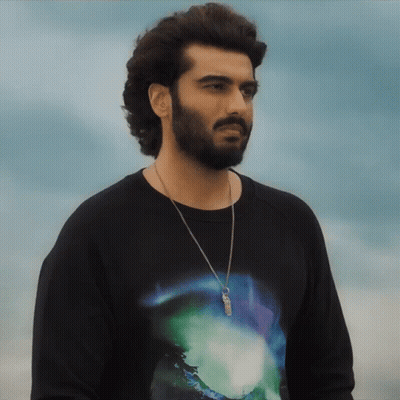 A Man With A Beard Wearing A Black Shirt With A Necklace Around His Neck GIF