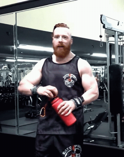 A Man With A Beard Wearing A Black Tank Top That Says ' Elite ' On The Front GIF