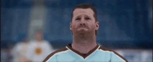 A Man With A Beard Wearing A Blue And Brown Hockey Jersey Is Crying On The Ice . GIF