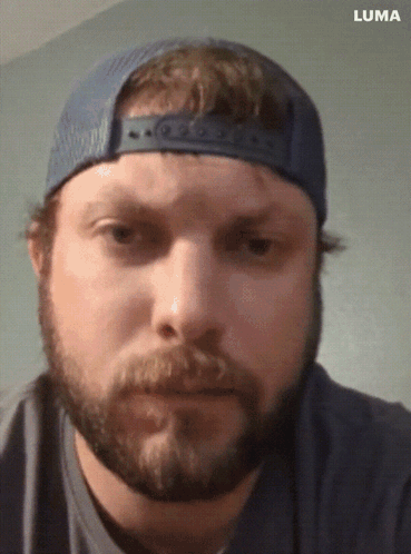 A Man With A Beard Wearing A Blue Hat And A Luma Logo On The Bottom GIF