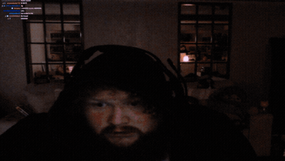 A Man With A Beard Wearing A Blue Robe And Headphones Looks At The Camera GIF