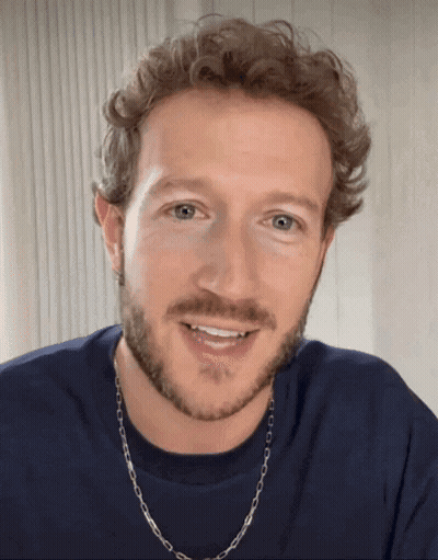 A Man With A Beard Wearing A Blue Shirt And A Silver Chain Around His Neck GIF