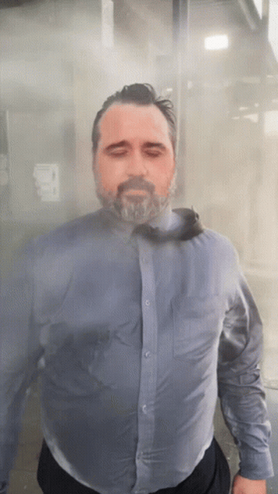 A Man With A Beard Wearing A Blue Shirt And Tie Is Standing In A Foggy Room GIF