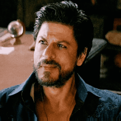A Man With A Beard Wearing A Blue Shirt Is Looking At The Camera GIF