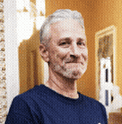 A Man With A Beard Wearing A Blue Shirt Is Smiling . GIF
