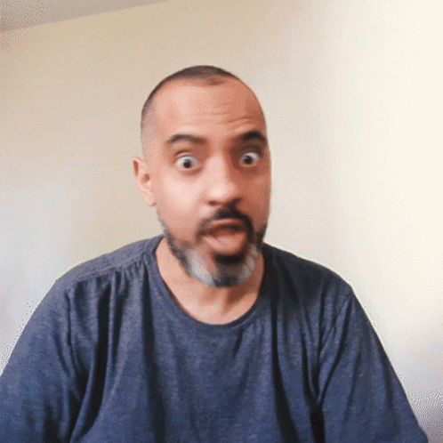 A Man With A Beard Wearing A Blue Shirt Makes A Surprised Face GIF
