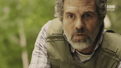 A Man With A Beard Wearing A Bullet Proof Vest Is Looking At The Camera . GIF