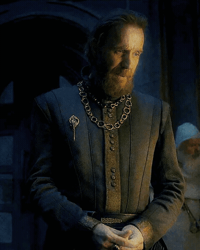 A Man With A Beard Wearing A Chain Around His Neck And A Brooch GIF
