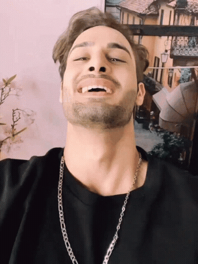 A Man With A Beard Wearing A Chain Around His Neck Smiles GIF