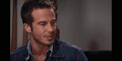 A Man With A Beard Wearing A Denim Jacket Looks Down At Something GIF