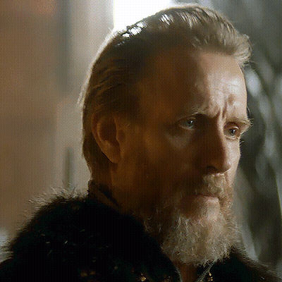 A Man With A Beard Wearing A Fur Coat Looks At The Camera GIF