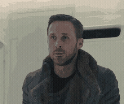 A Man With A Beard Wearing A Fur Coat Looks At The Camera GIF