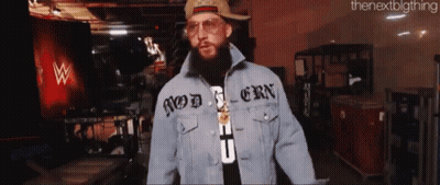 A Man With A Beard Wearing A Hat And A Denim Jacket That Says Modern On It GIF