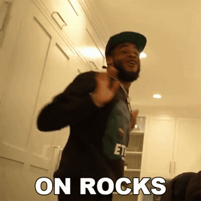 A Man With A Beard Wearing A Hat And A Shirt That Says " On Rocks " On It GIF