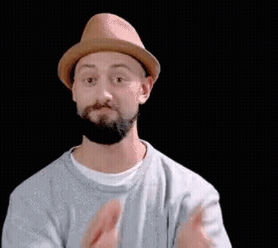 A Man With A Beard Wearing A Hat And A White Shirt Is Clapping His Hands . GIF