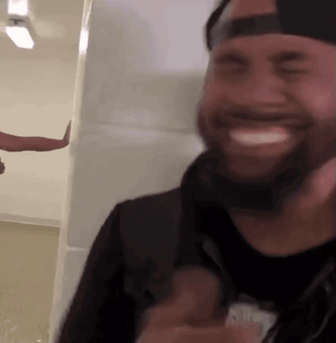 A Man With A Beard Wearing A Hat Is Smiling GIF