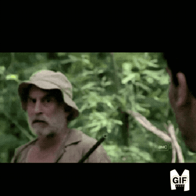 A Man With A Beard Wearing A Hat Is Talking To Another Man In The Woods GIF