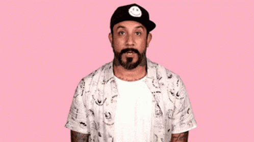 A Man With A Beard Wearing A Hat With A Smiley Face On It Says Oops I Did It Again GIF