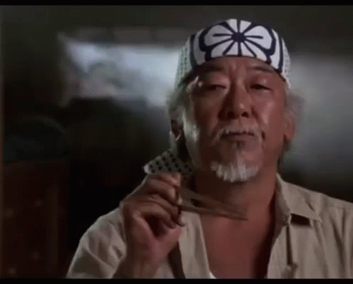 A Man With A Beard Wearing A Headband Is Holding A Pair Of Scissors . GIF