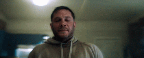 A Man With A Beard Wearing A Hoodie Is Standing In A Room . GIF