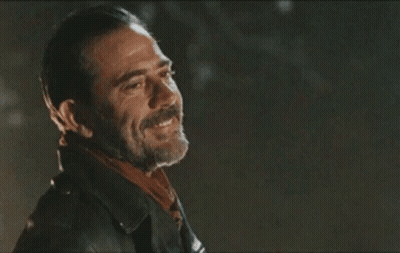 A Man With A Beard Wearing A Leather Jacket And Scarf Is Smiling . GIF