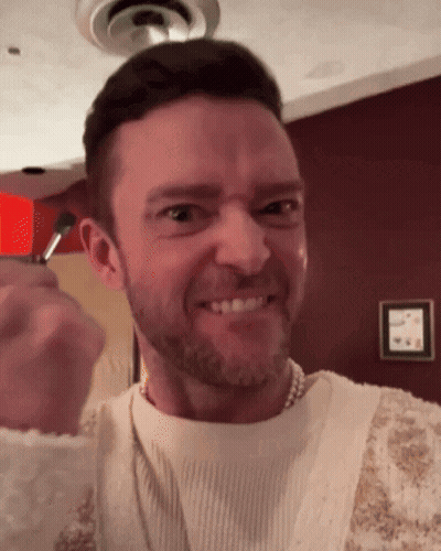 A Man With A Beard Wearing A Pearl Necklace Is Making A Funny Face GIF