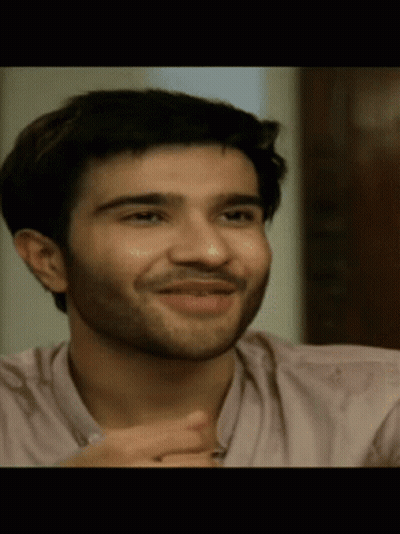 A Man With A Beard Wearing A Pink Shirt Is Smiling GIF