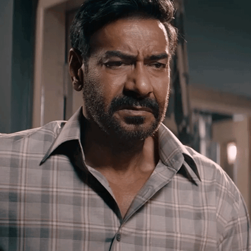 A Man With A Beard Wearing A Plaid Shirt Is Looking At The Camera GIF