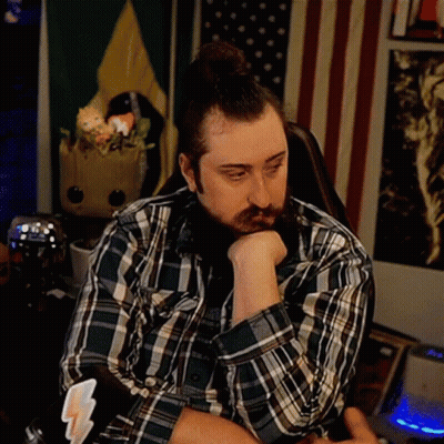 A Man With A Beard Wearing A Plaid Shirt Is Sitting In A Chair With His Head Resting On His Hand . GIF