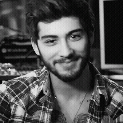 A Man With A Beard Wearing A Plaid Shirt Is Smiling In A Black And White Photo GIF