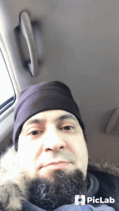 A Man With A Beard Wearing A Purple Hat Is Sitting In The Back Seat Of A Vehicle GIF