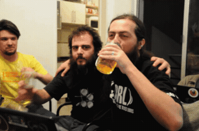 A Man With A Beard Wearing A Shirt That Says Erl Drinks From A Glass GIF