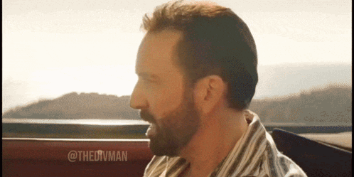 A Man With A Beard Wearing A Striped Shirt Is Sitting In A Car GIF