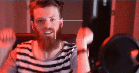 A Man With A Beard Wearing A Striped Shirt Is Smiling GIF