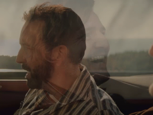 A Man With A Beard Wearing A Striped Shirt Looks Out The Window GIF