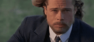 A Man With A Beard Wearing A Suit And Tie Is Looking At The Camera . GIF