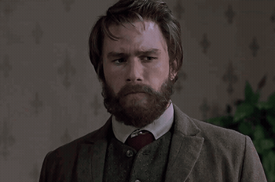 A Man With A Beard Wearing A Suit And Tie Looks At The Camera GIF
