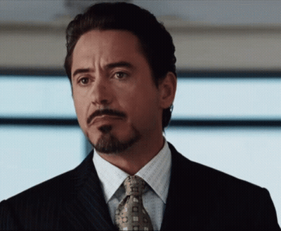 A Man With A Beard Wearing A Suit And Tie Looks To The Side GIF