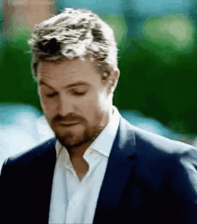 A Man With A Beard Wearing A Suit And White Shirt Is Looking Down . GIF