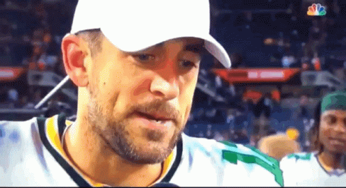 A Man With A Beard Wearing A White Hat And A Green Jersey GIF