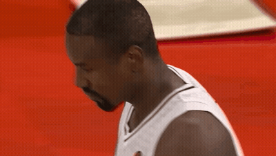 A Man With A Beard Wearing A White Jersey Looks Down At Something GIF