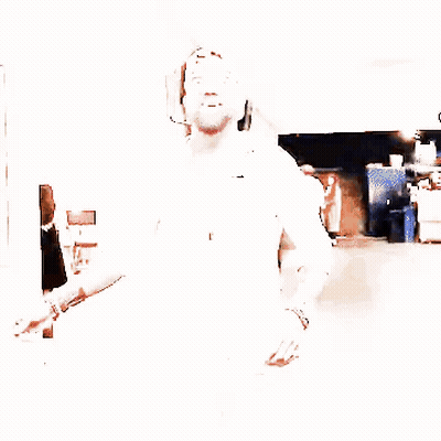 A Man With A Beard Wearing A White Shirt And A Baseball Cap Is Walking Down A Hallway . GIF