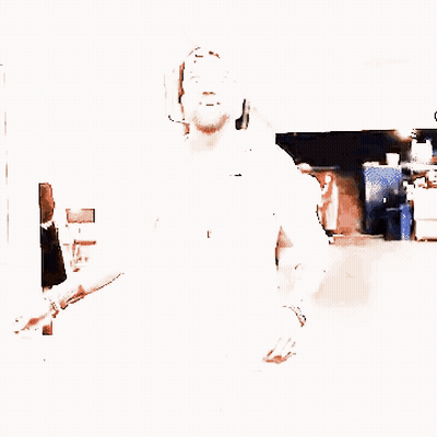 A Man With A Beard Wearing A White Shirt And A Baseball Cap Is Walking Down A Hallway . GIF