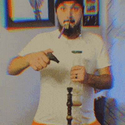 A Man With A Beard Wearing A White Shirt And A Black Hat Smoking A Cigarette GIF