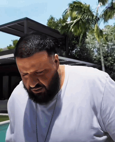 A Man With A Beard Wearing A White Shirt And A Chain Around His Neck GIF