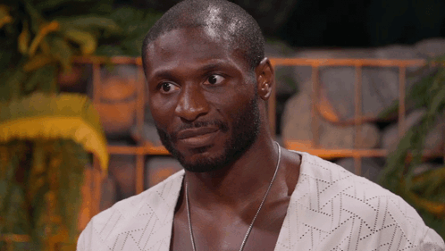 A Man With A Beard Wearing A White Shirt And A Necklace GIF