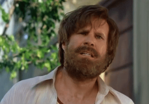 A Man With A Beard Wearing A White Shirt Is Making A Funny Face GIF