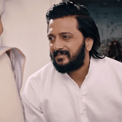 A Man With A Beard Wearing A White Shirt Is Smiling GIF