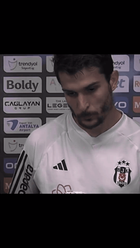 A Man With A Beard Wearing A White Shirt That Says Boldy On It GIF